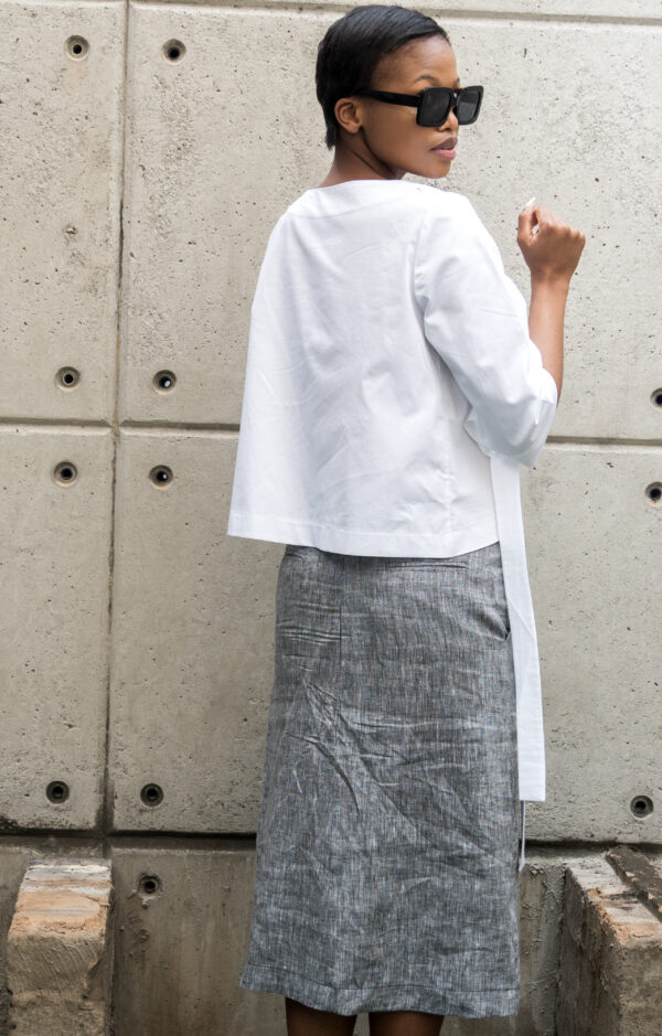 A back view image of a woman wearing white asymmetric white top