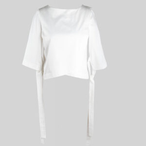 An image of an asymmetrical white. cotton top with strap details